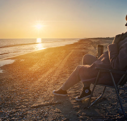 Frau mit Stuhl am Strand