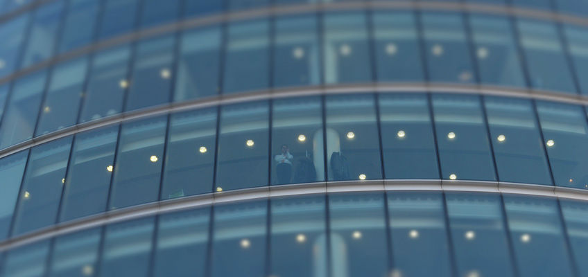 Mann schaut aus Bürogebäude runter