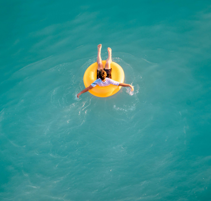 Junge sitzt auf Schwimmreifen im Pool